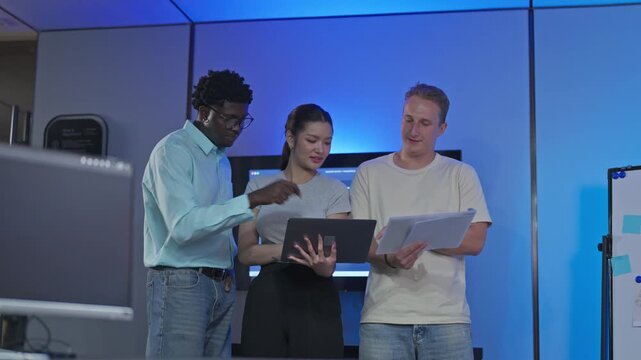 Diverse team of developers and programmers collaborate using tablets and laptops, demonstrating teamwork, knowledge exchange, and cross-functional problem-solving workflow.
