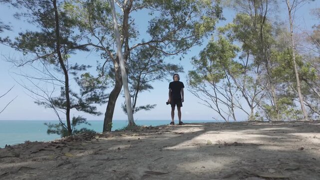 Young Asian Man Walking and Standing with Camera Overlooking Ocean in Kebumen, Indonesia