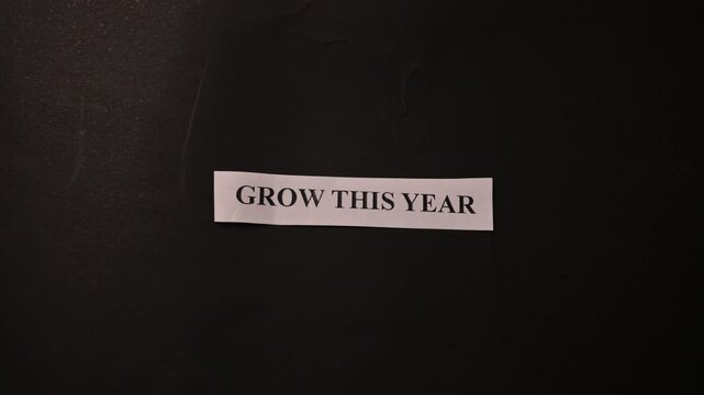 Grow This Year Text on Tiny Paper Placed on Black Book Background