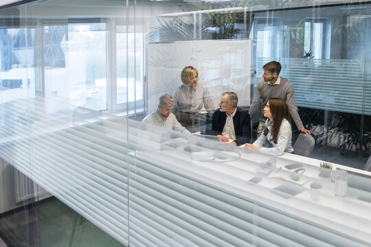 Creative business people, planning and meeting and brainstorming, ideas or strategy at office, view from glass wall.
