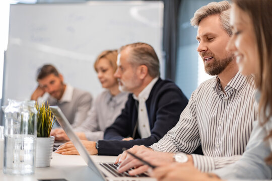 Successful businesspeople working in a coworking space working with laptop discussing strategy and business plan in modern office.