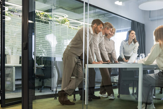 Creative business people, planning and meeting and brainstorming, ideas or strategy at office, view from glass wall.