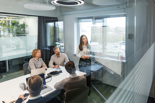 Creative business people, planning and meeting and brainstorming, ideas or strategy at office, view from glass wall.