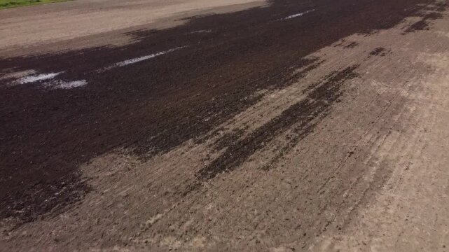 Aerial view of farmland soil moisture patterns. Drone footage showing agricultural earth texture.