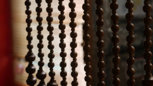 Close-up of decorative hanging wooden bead curtain with warm orange light filtering through in vintage retro interior cafe or shop