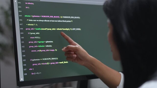 Computer screen showing C language source code with syntax highlighting and line numbers while a finger points at a function, programming and software development detail