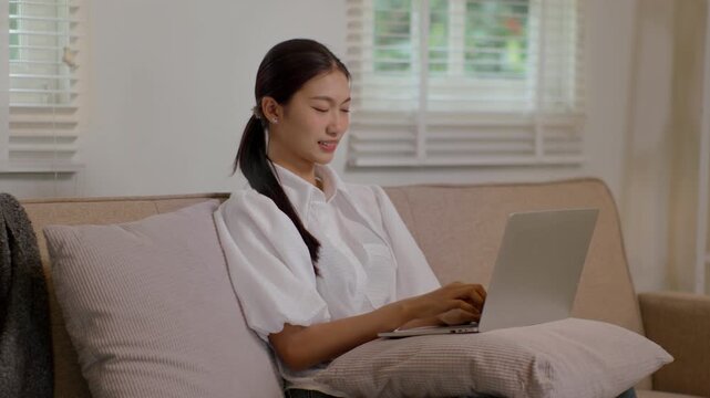 Woman using laptop on couch in warm cozy living room