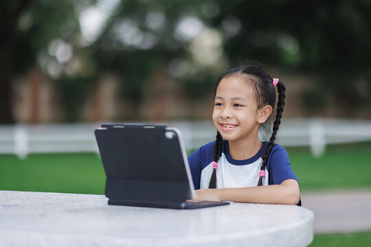 Asian girl smiling while learning using tablet outdoors