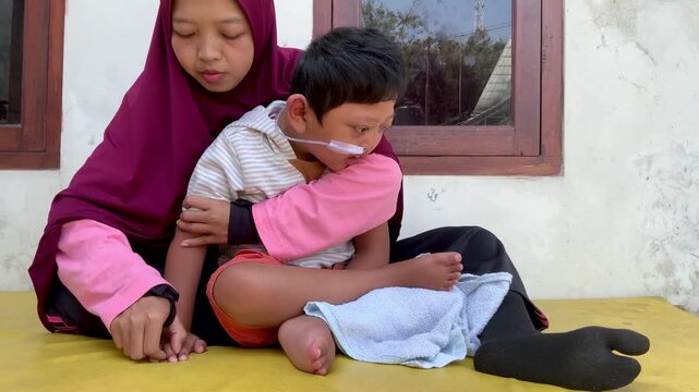 Mother supporting a child with a disability and nasal cannula in a home setting