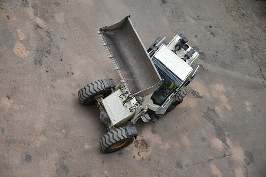 Aerial view of construction site where a front loader is loading soil, rocks, and debris into a dump truck, industrial work, excavation, and earthmoving processes