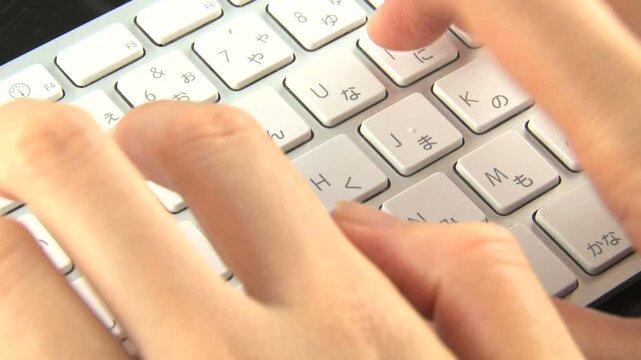 キーボードを打つ女性の指のクローズアップ