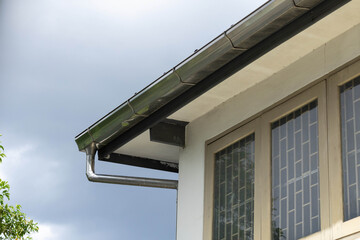 stainless steel gutter and downpipe in close-up view. © Rattanachat