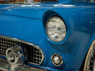 Classic car 1950s in bright blue, chrome grille and round headlight. © SKfoto GE