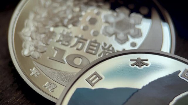 Macro video of a Japanese 1000 yen silver proof commemorative coin from Yamagata Prefecture, featuring a colorized scenic landscape, cherry motif, engraved lettering, and polished metallic surface.