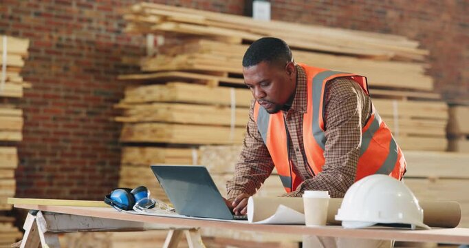 Carpenter, workshop and man on laptop for schedule, planning and email for furniture order. Construction, typing and African person on tech for review, inventory list or woodworking production report