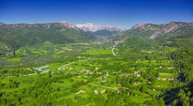 Aerial panorama of lush green mountain valley with scattered village homes. Travel concept.