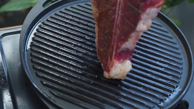 Man grilling a porterhouse steak over cast iron griddle, the smoke is visible through the high-heat sear, suitable for summer grill theme 