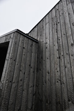 Low-angle portrait view of modern architecture clad in black Shou Sugi Ban timber, showing intersecting walls, charred grain, angular rooflines, and sky copy space
