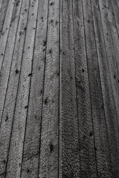 Detailed close-up of black charred timber boards with cracked grain, knots, vertical lines, and a pronounced corner formed by Shou Sugi Ban cladding