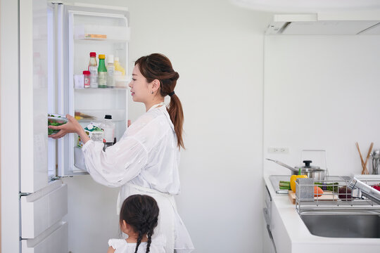 キッチンで冷蔵庫を開け料理を作る家族