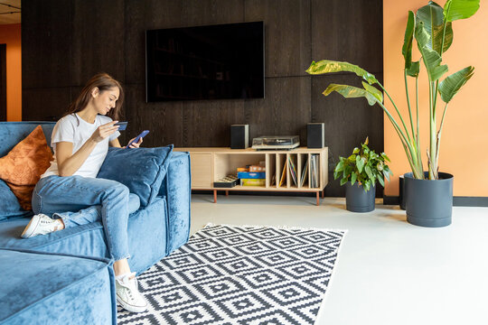 Long-haired woman with a phone and a credit card in hands
