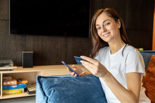 Long-haired woman with a phone and a credit card in hands