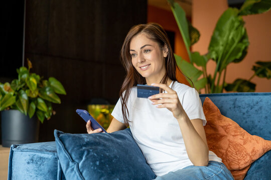 Young woman buying something online and looking contented