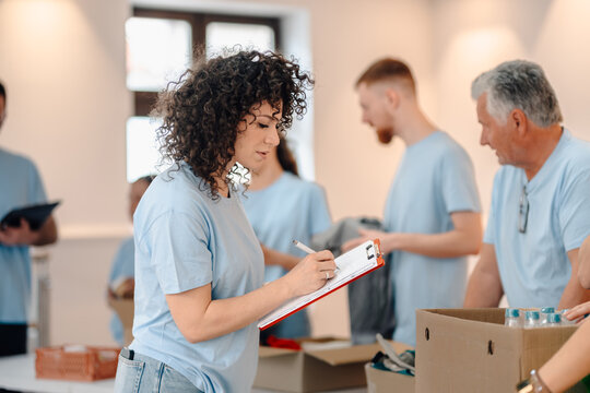 Woman volunteer writing on clipboard organizing donations