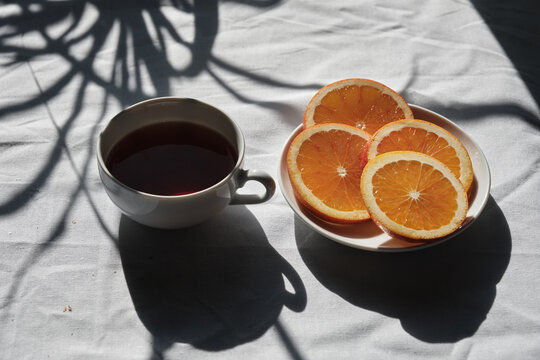 Tea in a cup served with oranges on a table