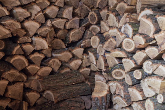 Pile of split firewood stacked for drying and winter heating. Natural wood texture, renewable fuel and rural household concept.
