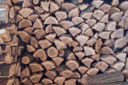 Pile of split firewood stacked for drying and winter heating. Natural wood texture, renewable fuel and rural household concept.