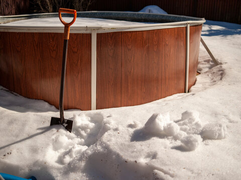 shovelling snow around above ground pool