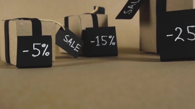 Promotional video featuring brown cardboard gift boxes with black ribbons and tags indicating percentage discounts for a sale event, such as Black Friday or seasonal clearance sales