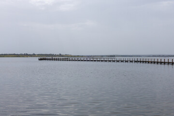 Fototapeta premium Long wooden pier extending across lake alentejo portugal