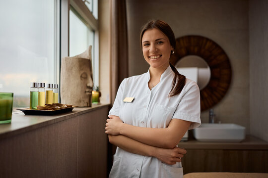 Confident female massage therapist working at wellness spa center and looking at camera.