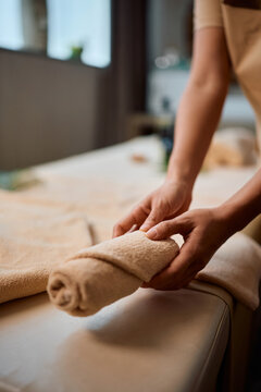 Close up of massage therapist folding clean towels in spa treatment room.