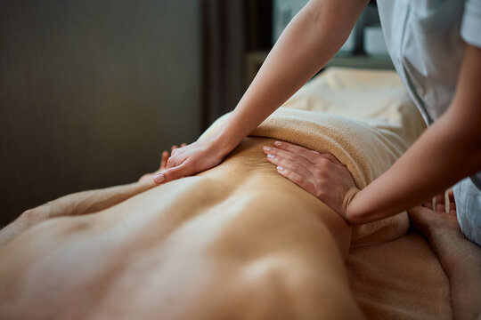 Close up of therapist massaging man's back during treatment at health spa.