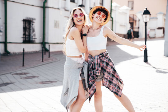 Two young beautiful smiling hipster female in trendy summer white t-shirt and shorts clothes. Sexy carefree women posing in the street. Positive models having fun, hugging and going crazy