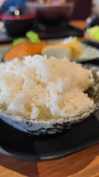 Steamed Japanese white rice in ceramic bowl on restaurant table
