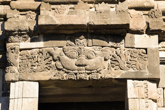 Weathered stone lintel features intricate Hindu relief carvings above an entrance at Prambanan Temple in Central Java, Indonesia.