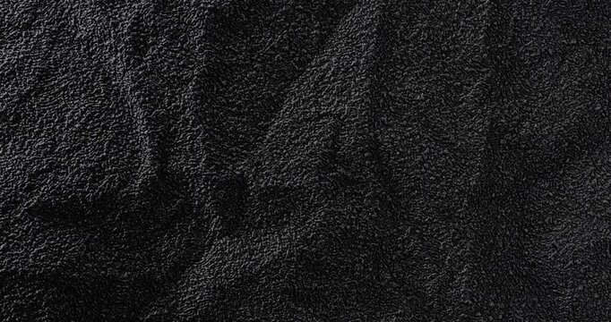Black Texture. Close-up of dark textured cloth with soft folds and shifting highlights. Useful as an abstract background.