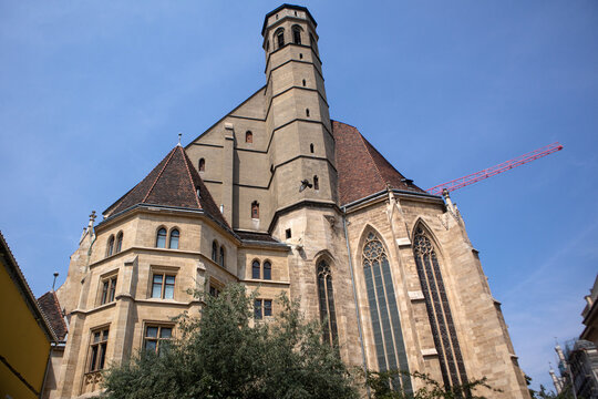 Facciata esterna e campanile ottagonale della Chiesa dei Minoriti Minoritenkirche in stile gotico sotto un cielo azzurro, storico luogo di culto e attrazione nel centro di Vienna, Austria.