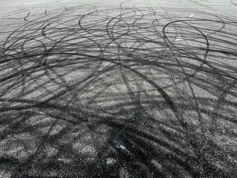 Black tire skid marks cover wet asphalt surface