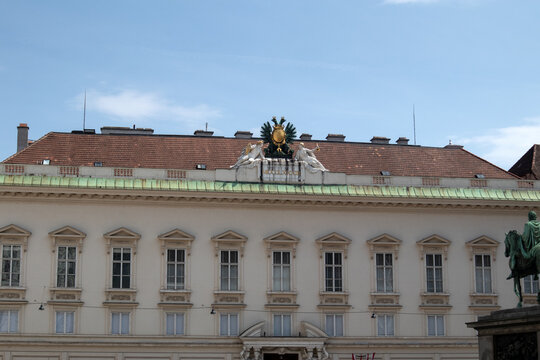 Dettaglio della facciata barocca del palazzo imperiale di Hofburg con finestre simmetriche e il monumentale stemma dell'aquila bicipite asburgica sul tetto in Josefsplatz a Vienna, Austria.