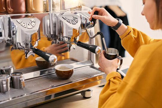 Barista steaming milk in a pitcher with coffee machine