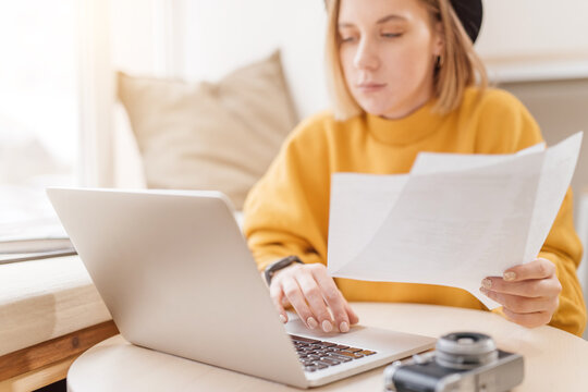Woman working with papers and on a laptop, typing on keyboard, close up
