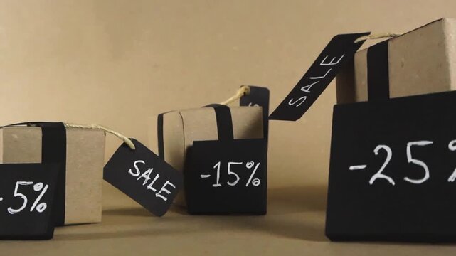 Promotional concept featuring cardboard gift boxes with black ribbons and tags showing various discount percentages, ideal for advertising seasonal sales events like Black Friday or clearance