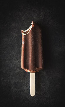 Bitten chocolate ice cream bar on dark background from above