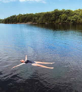 Woman floating on her back in a calm scenic lake