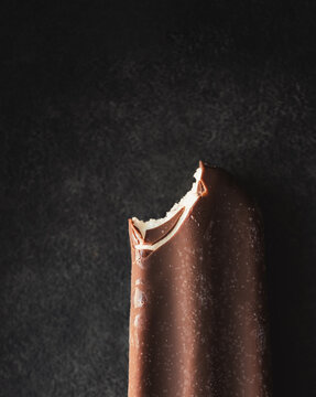 Close up of chocolate covered ice cream bar with a bite taken